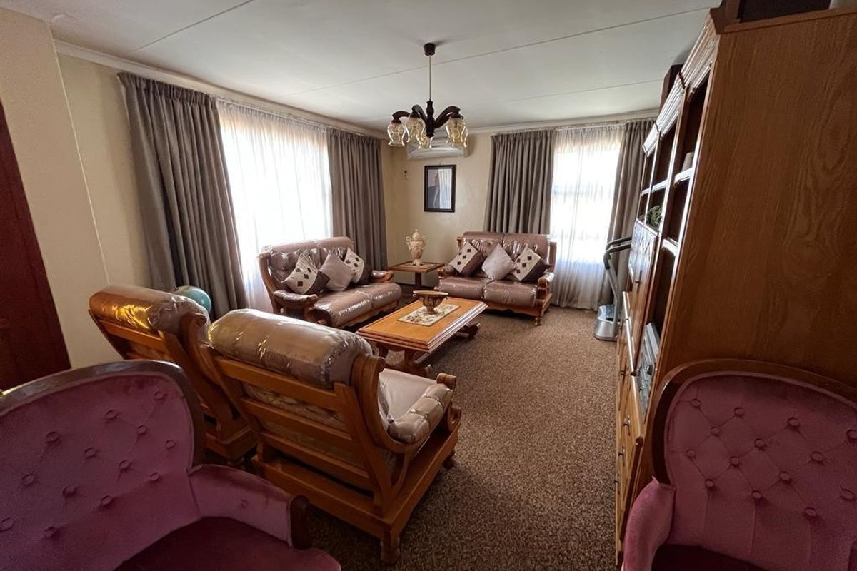 A traditional living room featuring wall-to-wall carpeting, neutral wall finishes, and an installed air conditioning unit.
