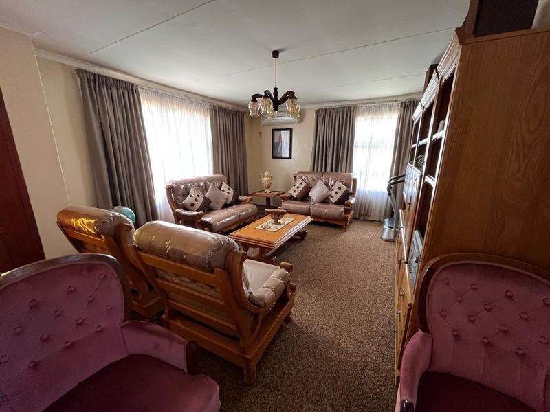 A traditional living room featuring wall-to-wall carpeting, neutral wall finishes, and an installed air conditioning unit.