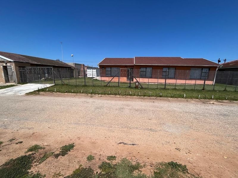 Front view of a single-story residential house featuring a tiled roof, brick exterior, and secure wire mesh perimeter fencing.