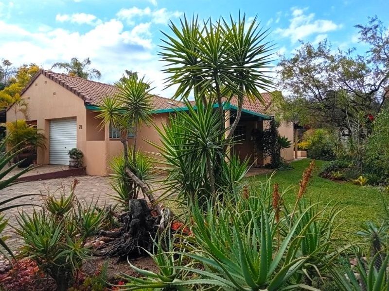 Front view of a retirement village unit featuring a paved driveway, single garage, and established garden surroundings.