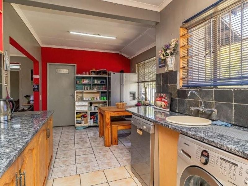 A functional kitchen featuring granite countertops, slate tile backsplash, and ceramic flooring, offering a practical layout with integrated cabinetry and utility space.