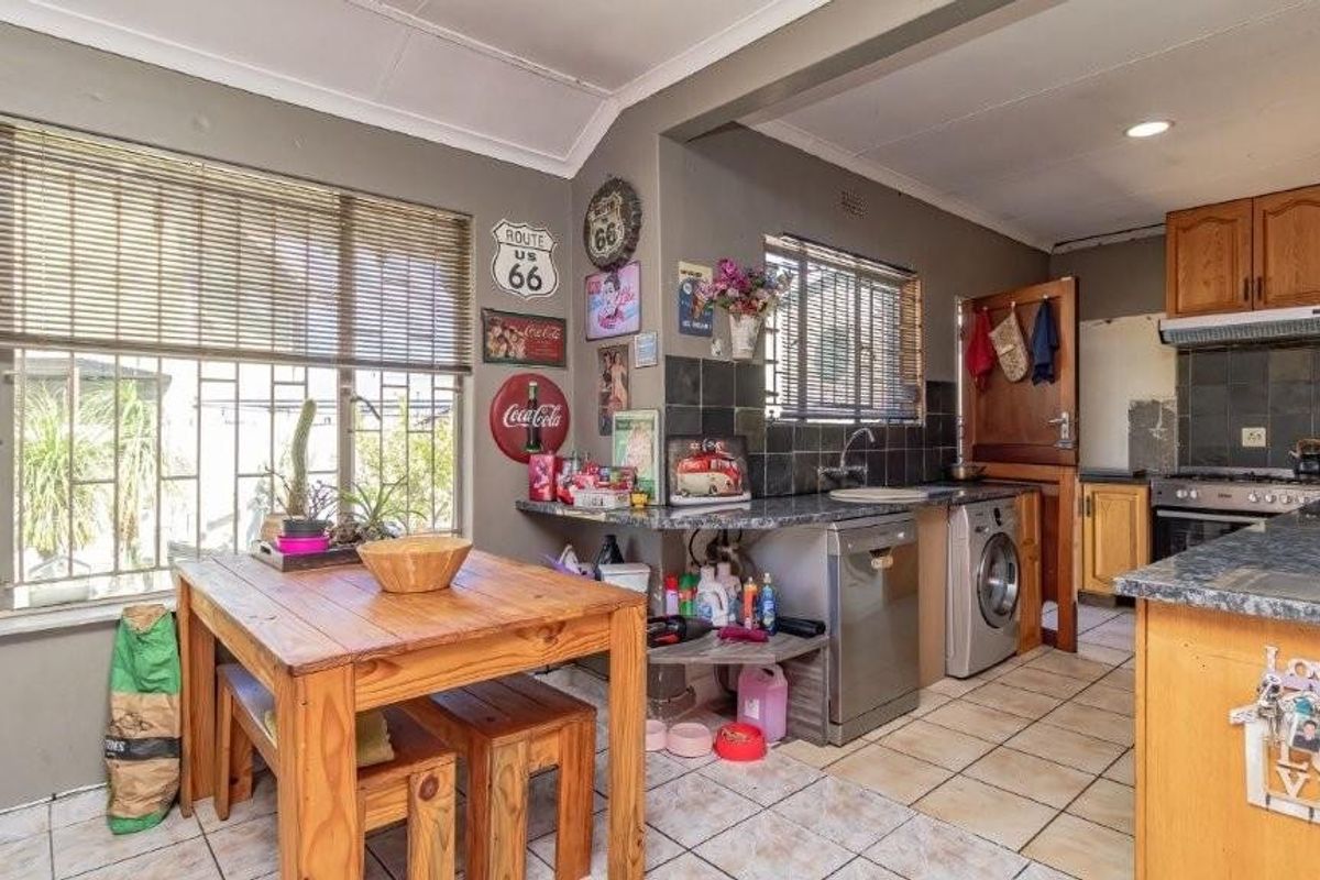 Functional kitchen featuring tiled flooring, built-in cabinetry, and a tiled backsplash, offering a practical layout with integrated appliances and natural light from large windows.
