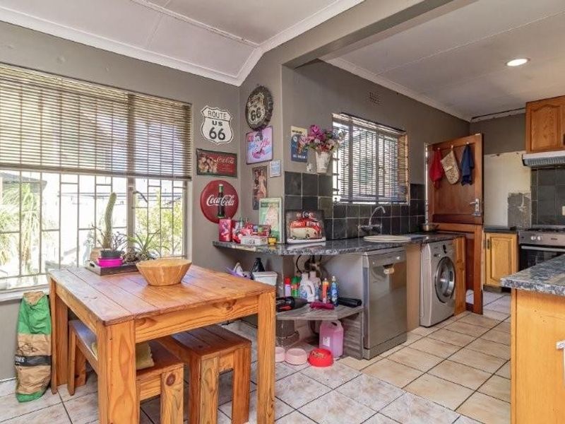 Functional kitchen featuring tiled flooring, built-in cabinetry, and a tiled backsplash, offering a practical layout with integrated appliances and natural light from large windows.