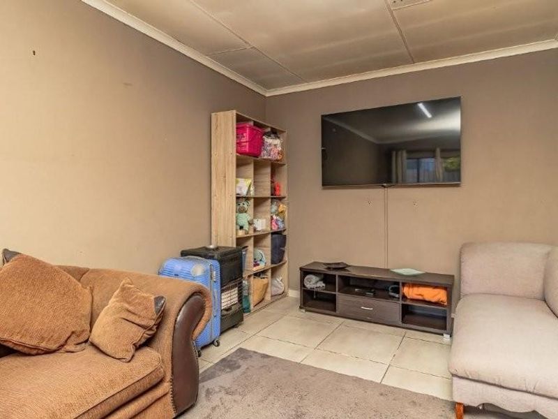A living room featuring tiled flooring and coved ceilings, currently used as a casual lounge area.