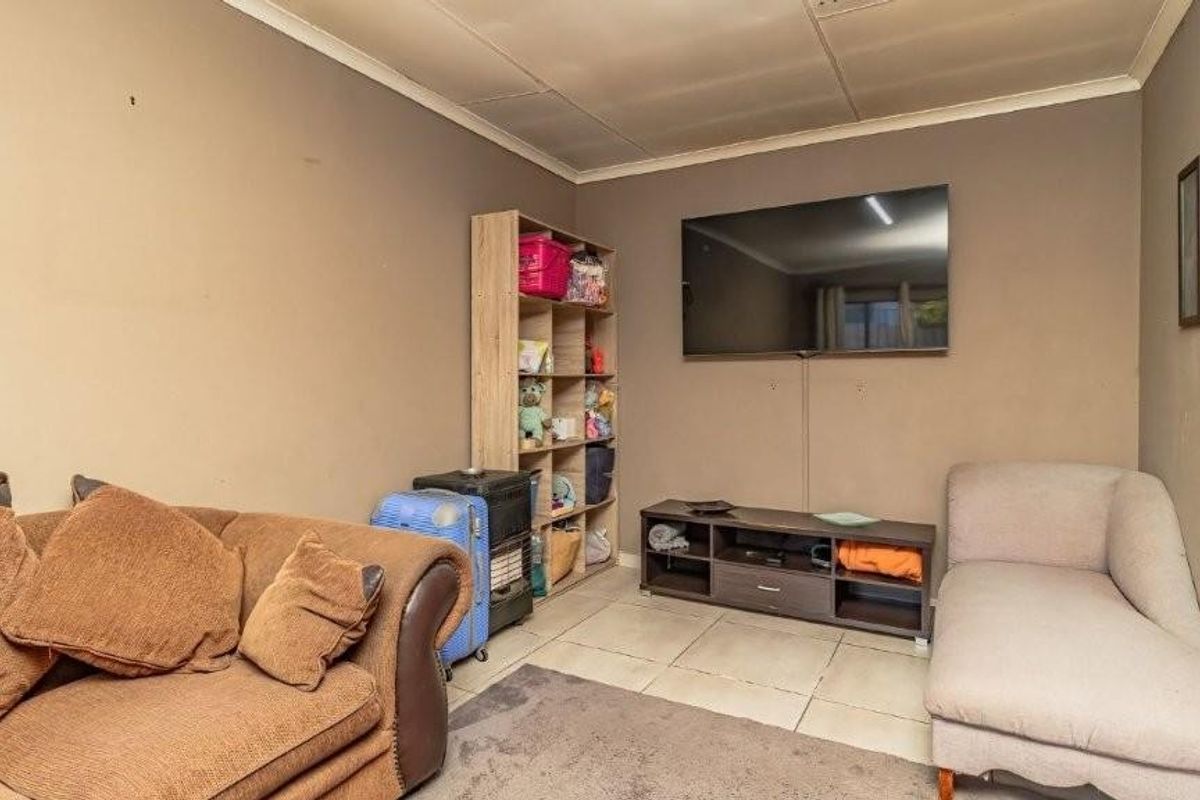 A living room featuring tiled flooring and coved ceilings, currently used as a casual lounge area.