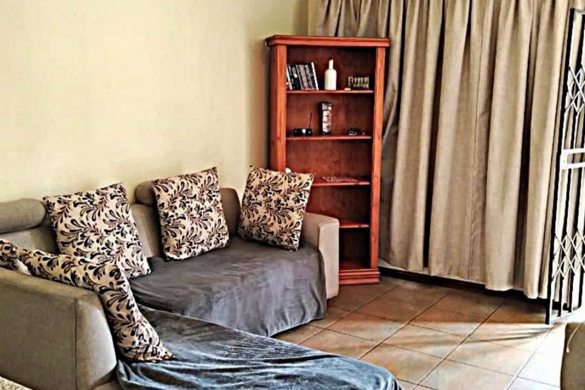A living room area featuring tiled flooring and a security gate leading to an outdoor space.