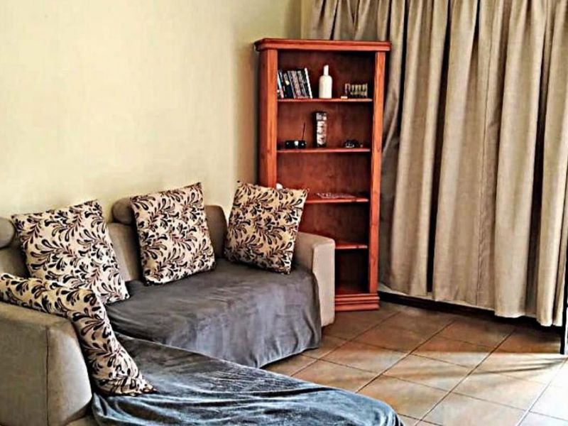 A living room area featuring tiled flooring and a security gate leading to an outdoor space.