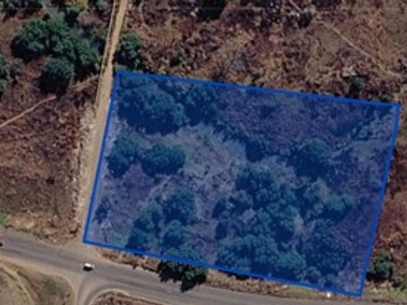 An aerial view of a vacant residential plot of land with natural vegetation, highlighting the property boundaries.