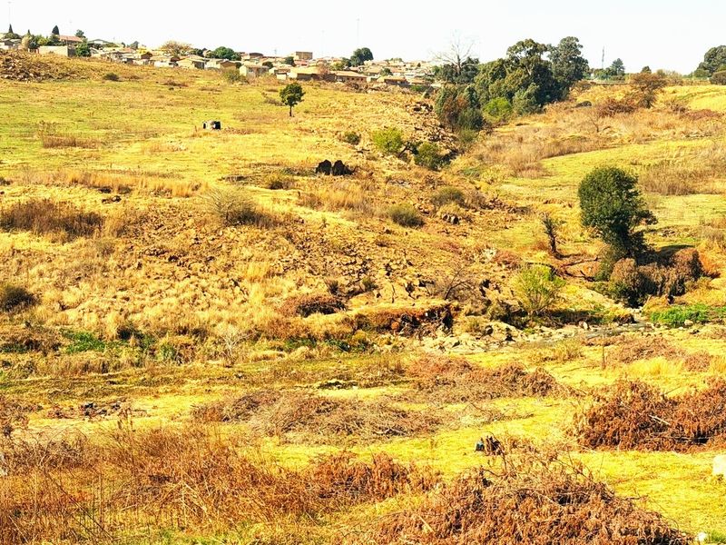 A wide-angle view of the vacant residential land, showcasing the natural sloped terrain and surrounding landscape.