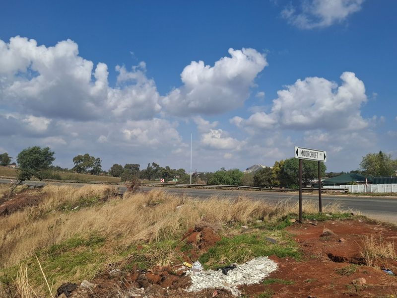 A view of the street frontage and surrounding landscape, showing the road access and local signage near the vacant land.