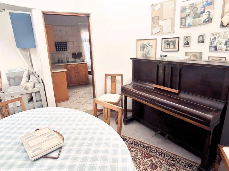 A living area featuring tiled flooring and an archway leading to the kitchen, providing a functional layout with potential for modern updates.
