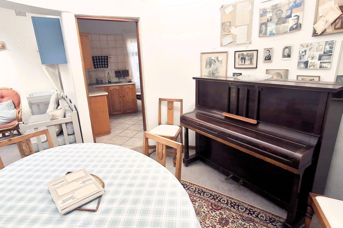 A living area featuring tiled flooring and an archway leading to the kitchen, providing a functional layout with potential for modern updates.