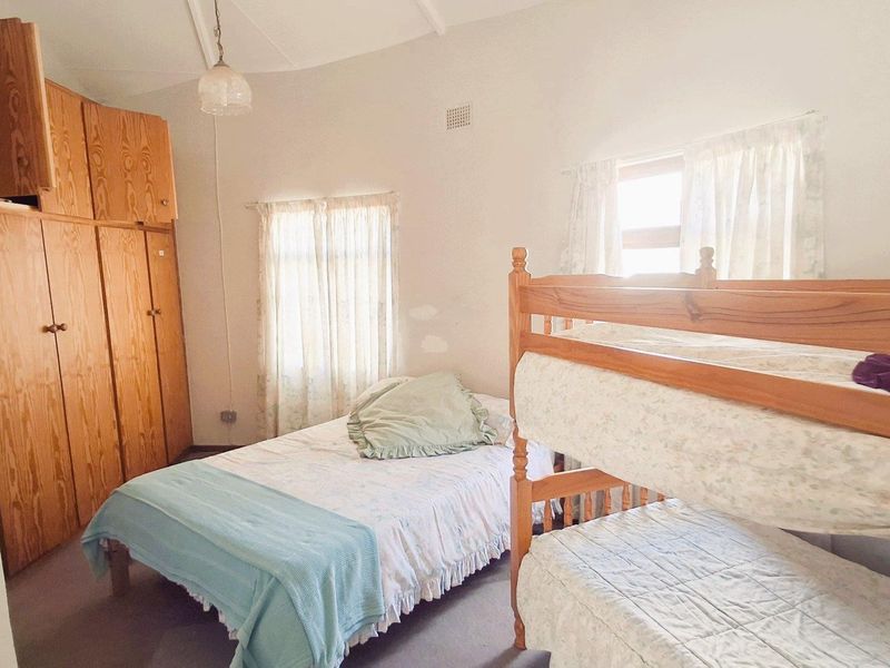 A bedroom featuring built-in wooden cabinetry and natural light, offering a functional space with potential for cosmetic updates.