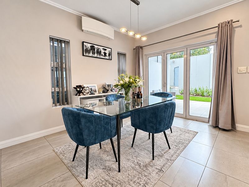 A bright dining room featuring tiled flooring, a split-system air conditioner, and sliding glass doors that provide direct access to the outdoor patio area.