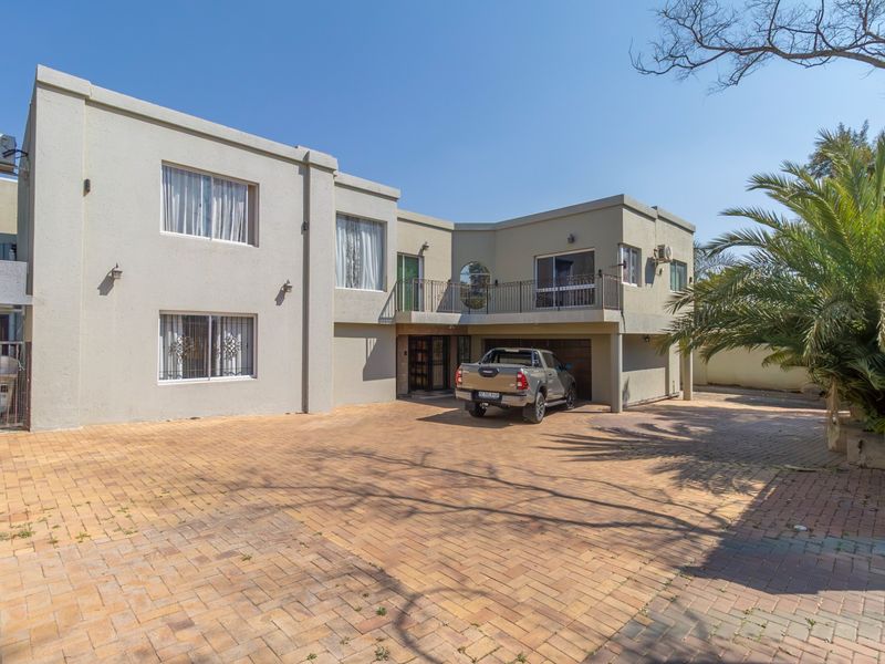 A two-story residential property featuring a paved driveway, integrated garage, and an upper-level balcony with wrought iron railings.