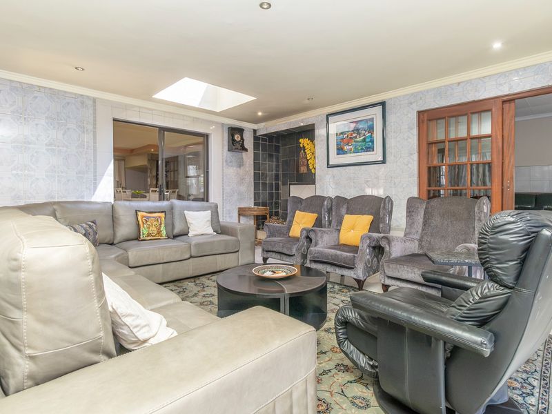 Spacious living room featuring a skylight, tiled wall finishes, and access to adjacent areas through sliding and French doors.
