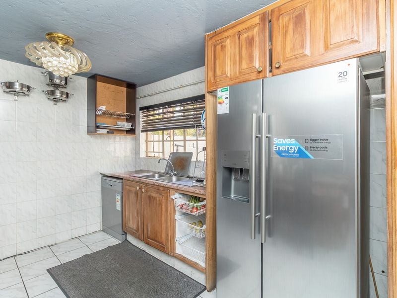 A functional kitchen featuring wooden cabinetry, tiled backsplash, and tiled flooring, offering a practical layout with potential for modern updates.