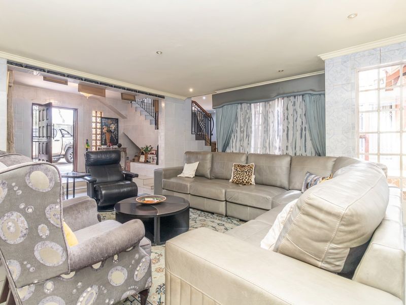Spacious living room featuring tiled flooring, recessed lighting, and an integrated staircase with a wrought iron balustrade.