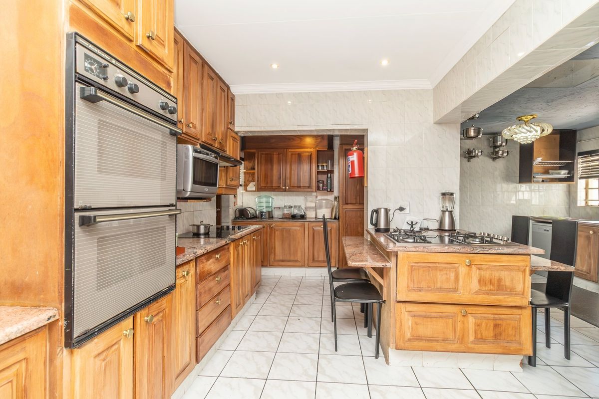 A functional kitchen featuring traditional wooden cabinetry, granite countertops, a built-in double oven, and a gas hob with a breakfast nook area.