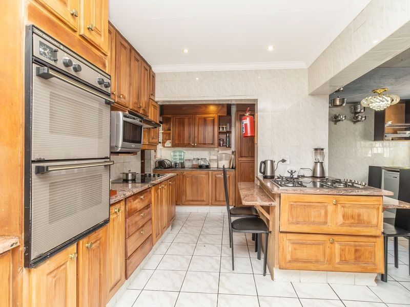 A functional kitchen featuring traditional wooden cabinetry, granite countertops, a built-in double oven, and a gas hob with a breakfast nook area.