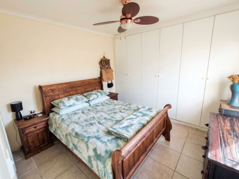 A bedroom featuring tiled flooring, a ceiling fan, and extensive built-in cupboard storage.