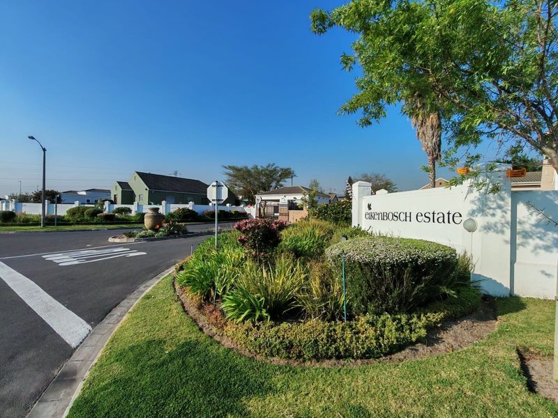Entrance view of Eikenbosch Estate featuring well-maintained landscaping, signage, and paved road access.