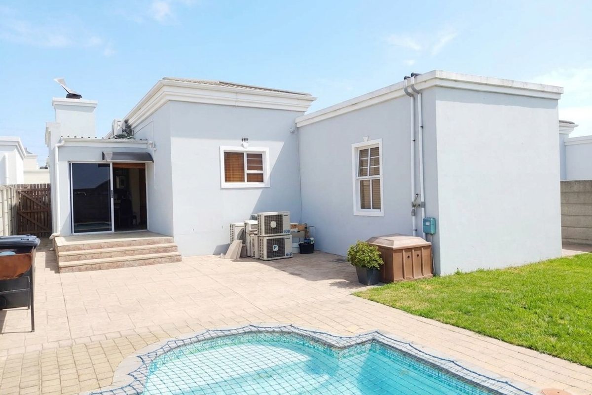 Rear exterior view featuring a paved patio area, a swimming pool with a safety net, and access to the home via a sliding glass door.
