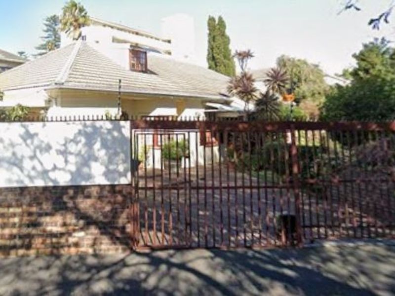 Front exterior view of the property featuring a tiled roof, brick boundary wall, and a metal security gate with electric fencing.
