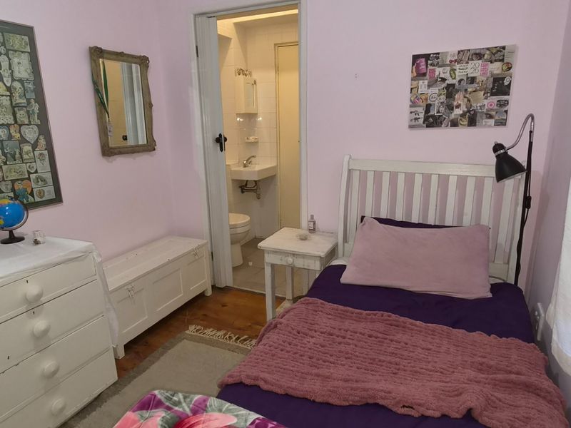 A cozy bedroom featuring hardwood flooring and direct access to an en-suite bathroom, offering a functional layout with soft wall tones.