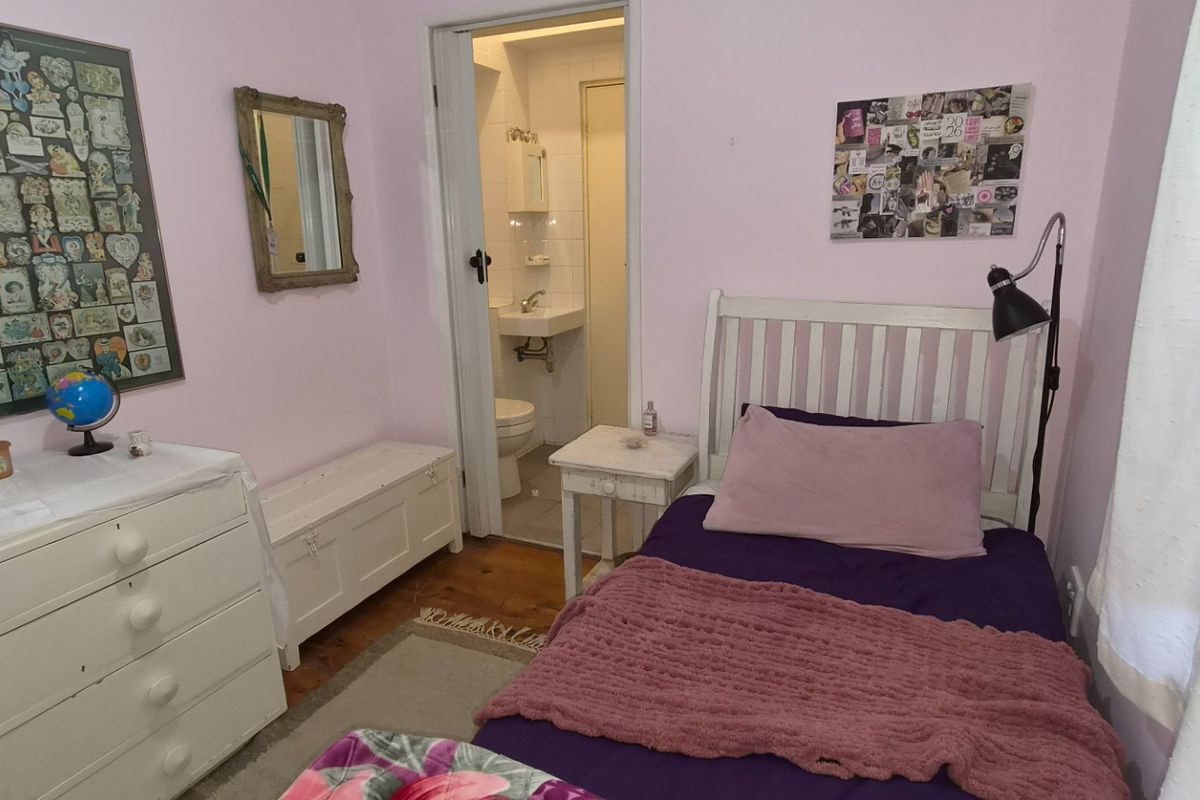 A cozy bedroom featuring hardwood flooring and direct access to an en-suite bathroom, offering a functional layout with soft wall tones.