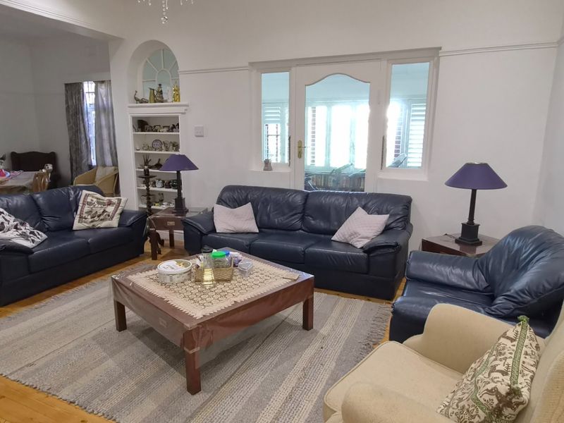 Spacious living room featuring original hardwood flooring, built-in shelving, and classic architectural details including picture rails and an arched doorway.