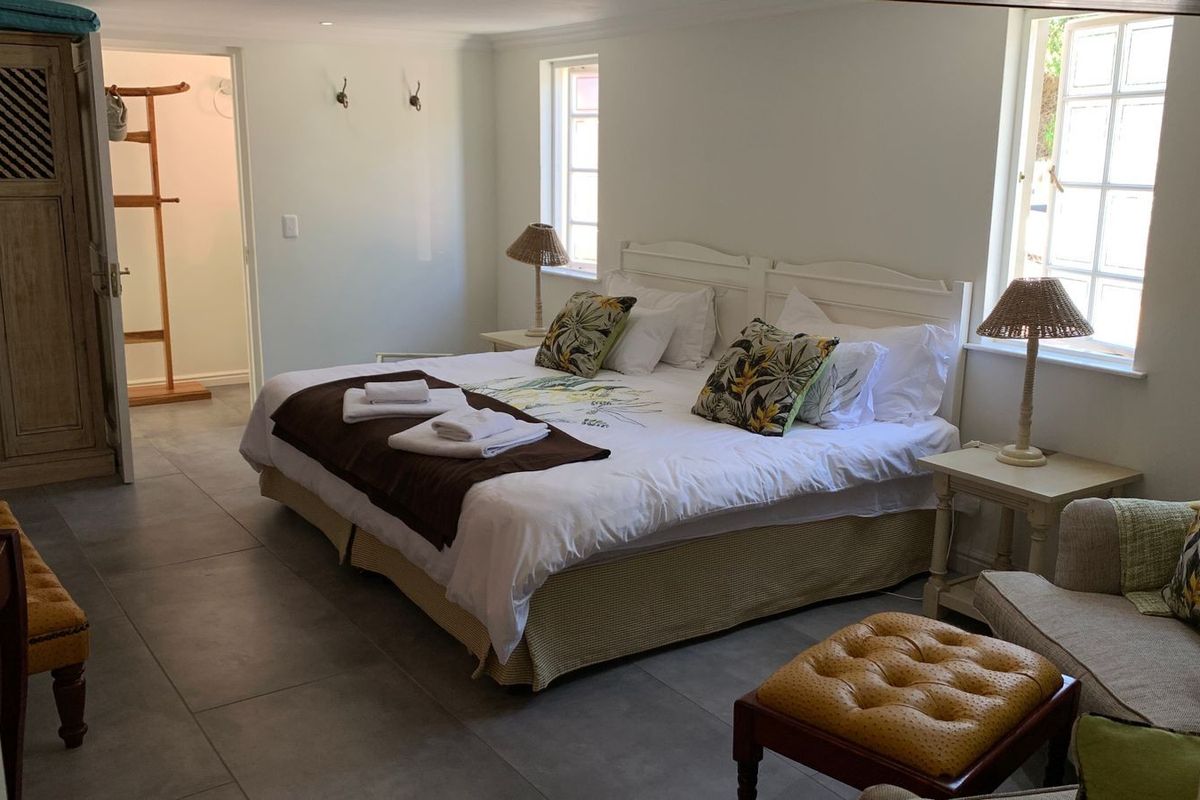 Spacious bedroom featuring neutral tiled flooring, built-in wardrobe storage, and natural light through multi-pane windows, leading into an adjoining dressing area.