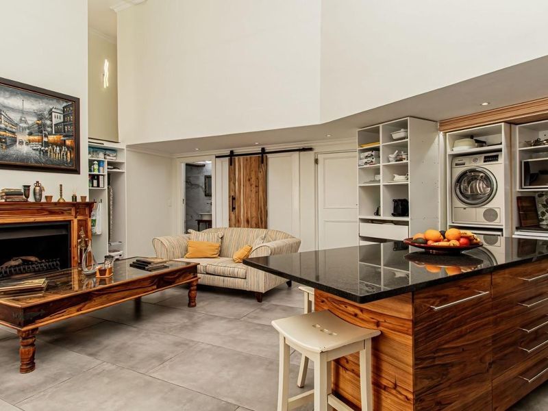 Spacious open-plan living area featuring a fireplace with a wooden mantel, a kitchen island with granite countertops, and integrated storage solutions.