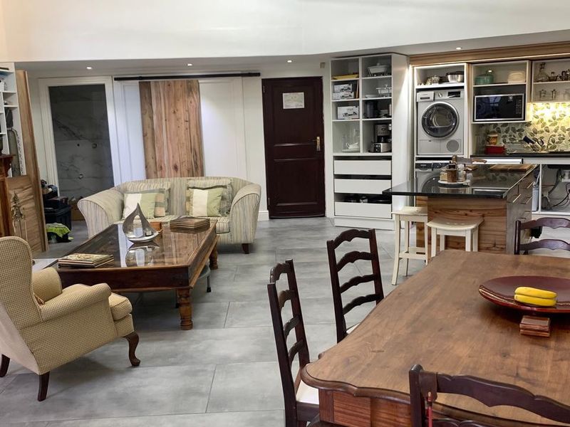 Spacious open-plan living area featuring a built-in fireplace, dining space, and a compact kitchen with integrated laundry appliances and stone countertops.