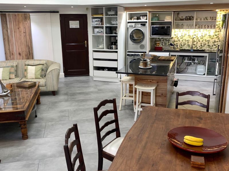Open-plan living and kitchen area featuring a central island, integrated laundry appliances, and tiled flooring, requiring minor finishing touches to cabinetry and walls.