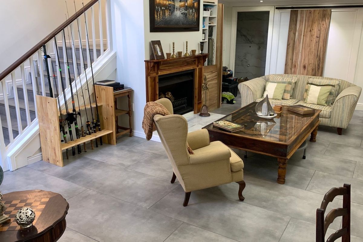 Spacious living room featuring large format floor tiles, a traditional fireplace with a wooden mantelpiece, and an integrated staircase.