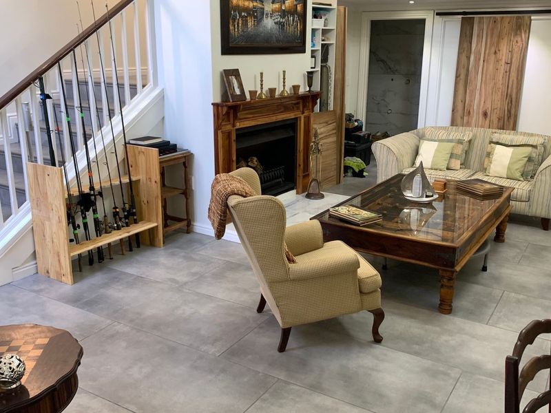 Spacious living room featuring large format floor tiles, a traditional fireplace with a wooden mantelpiece, and an integrated staircase.