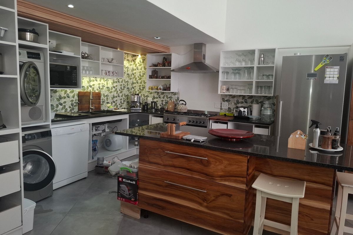 Modern kitchen featuring a wooden island with granite countertop, gas stove, extractor fan, and integrated laundry area with ample built-in cabinetry.