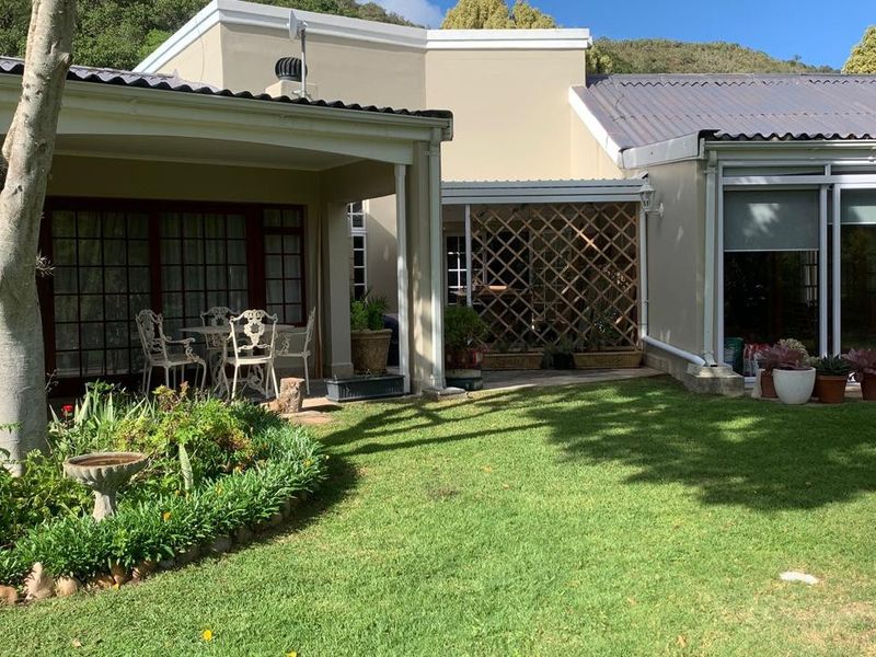 A well-maintained rear exterior view featuring a covered patio area, landscaped garden, and direct access to the home through sliding glass doors.