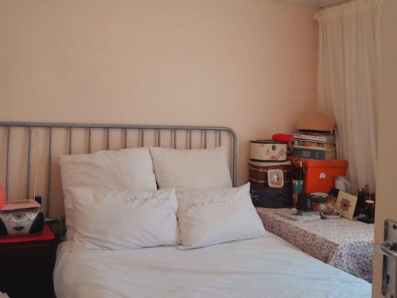 A compact bedroom featuring a metal bed frame and plain wall finishes, offering a functional space that could benefit from modern updates.