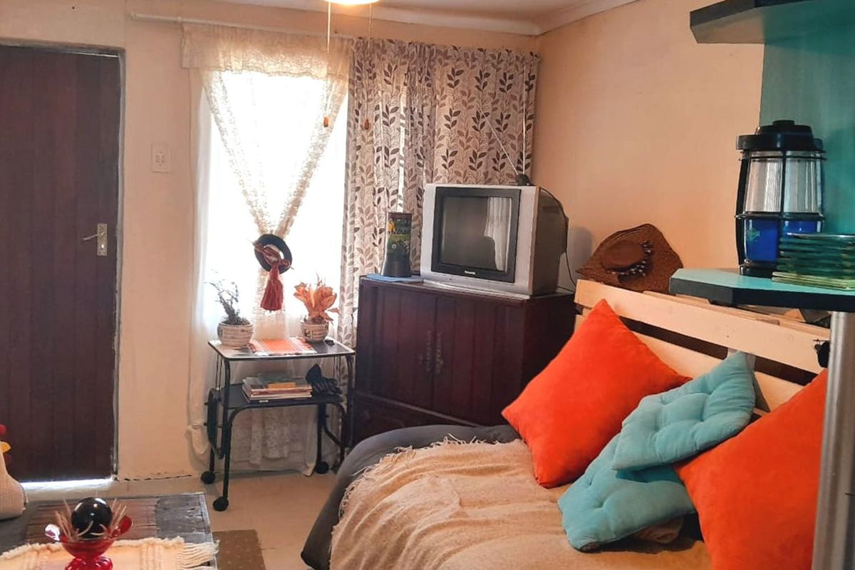 A compact living area featuring a ceiling fan and natural light from a window, offering a functional space for relaxation.