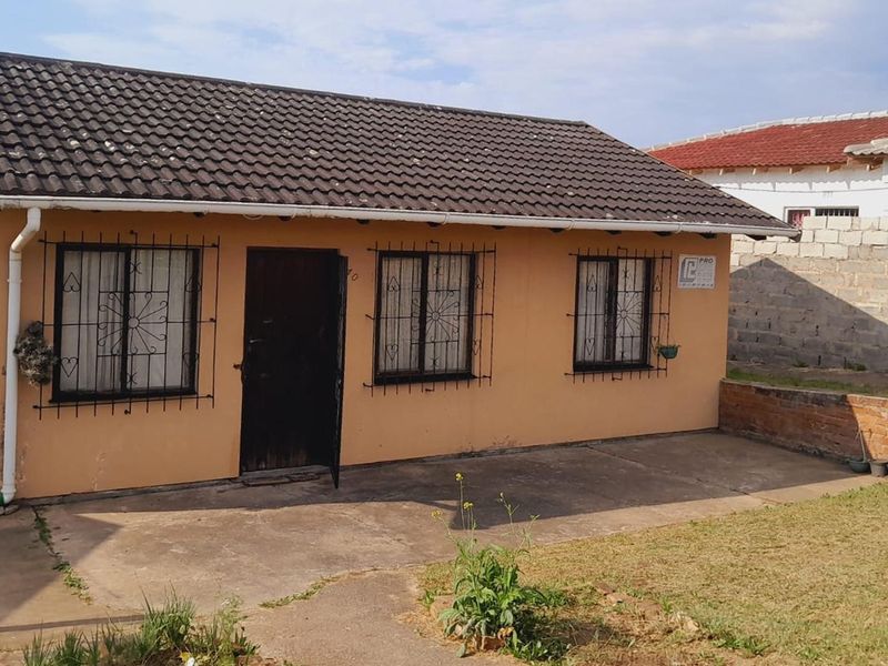 Front view of a single-story house featuring a tiled roof, security bars on windows, and a concrete driveway area.