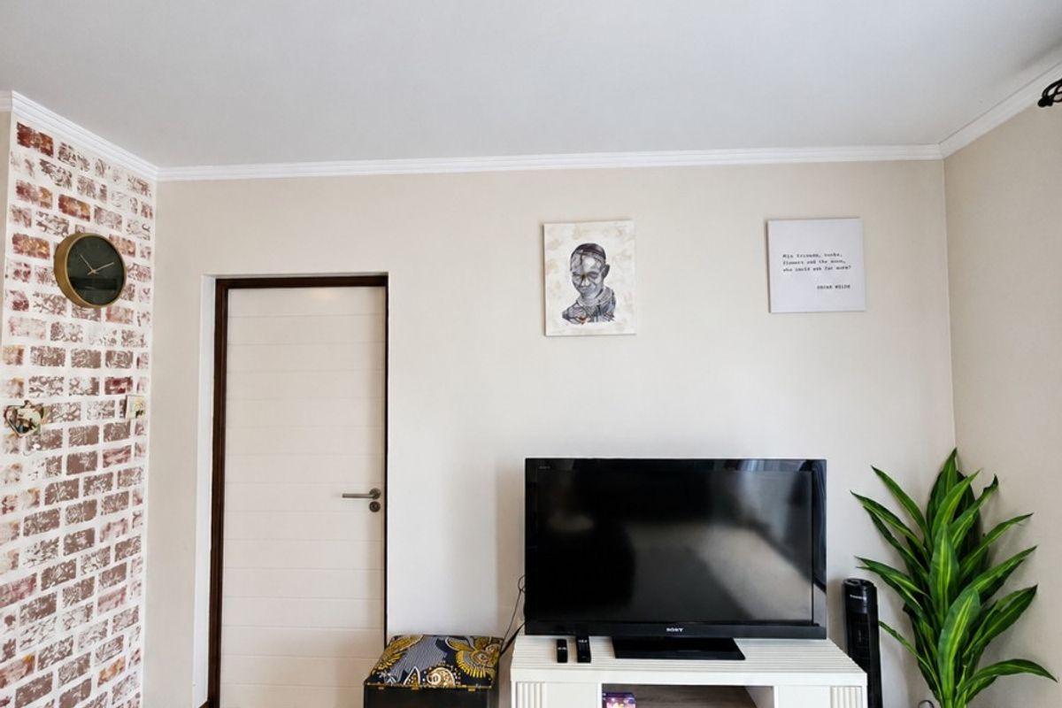 A well-maintained living room featuring a decorative exposed brick accent wall and neutral tiled flooring.