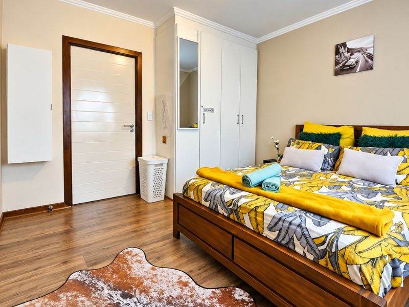 A well-maintained bedroom featuring laminate flooring, built-in wardrobes with a mirrored panel, and neutral wall finishes.