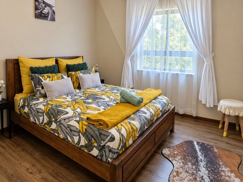 A well-maintained bedroom featuring laminate flooring, neutral wall tones, and a window with fitted curtain hardware.