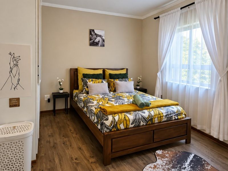 A well-maintained bedroom featuring laminate flooring, built-in wardrobe storage, and neutral wall finishes with natural light from the window.