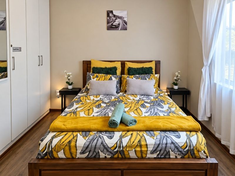 A well-maintained bedroom featuring laminate flooring, built-in cupboards, and a neutral color palette, offering a clean and functional living space.