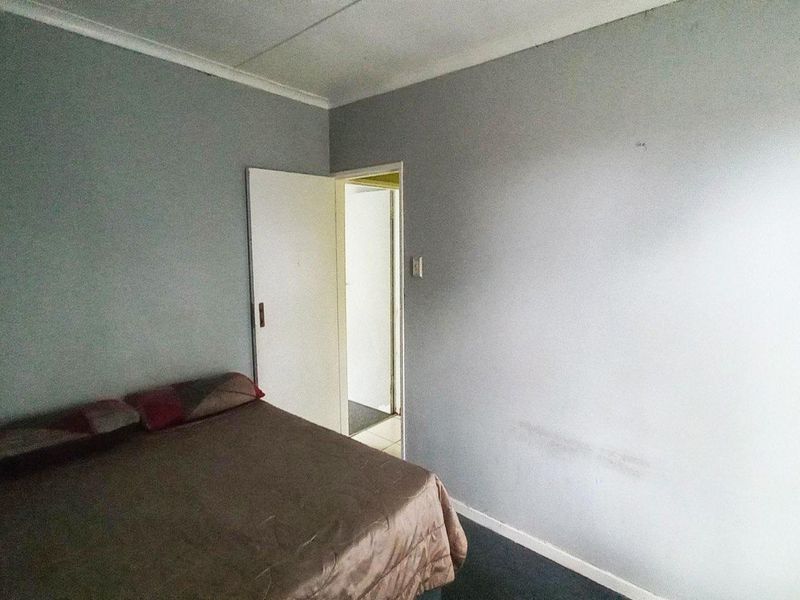 A bedroom featuring grey painted walls and coving, showing signs of wear on the wall surfaces.