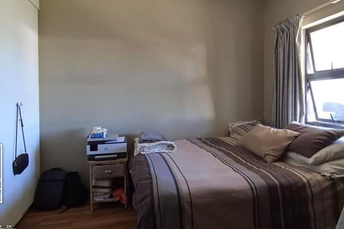 A standard bedroom featuring laminate flooring and an aluminium window frame, providing a functional space with natural light.
