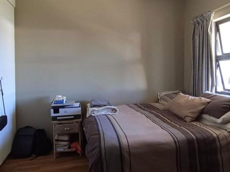 A standard bedroom featuring laminate flooring and an aluminium window frame, providing a functional space with natural light.